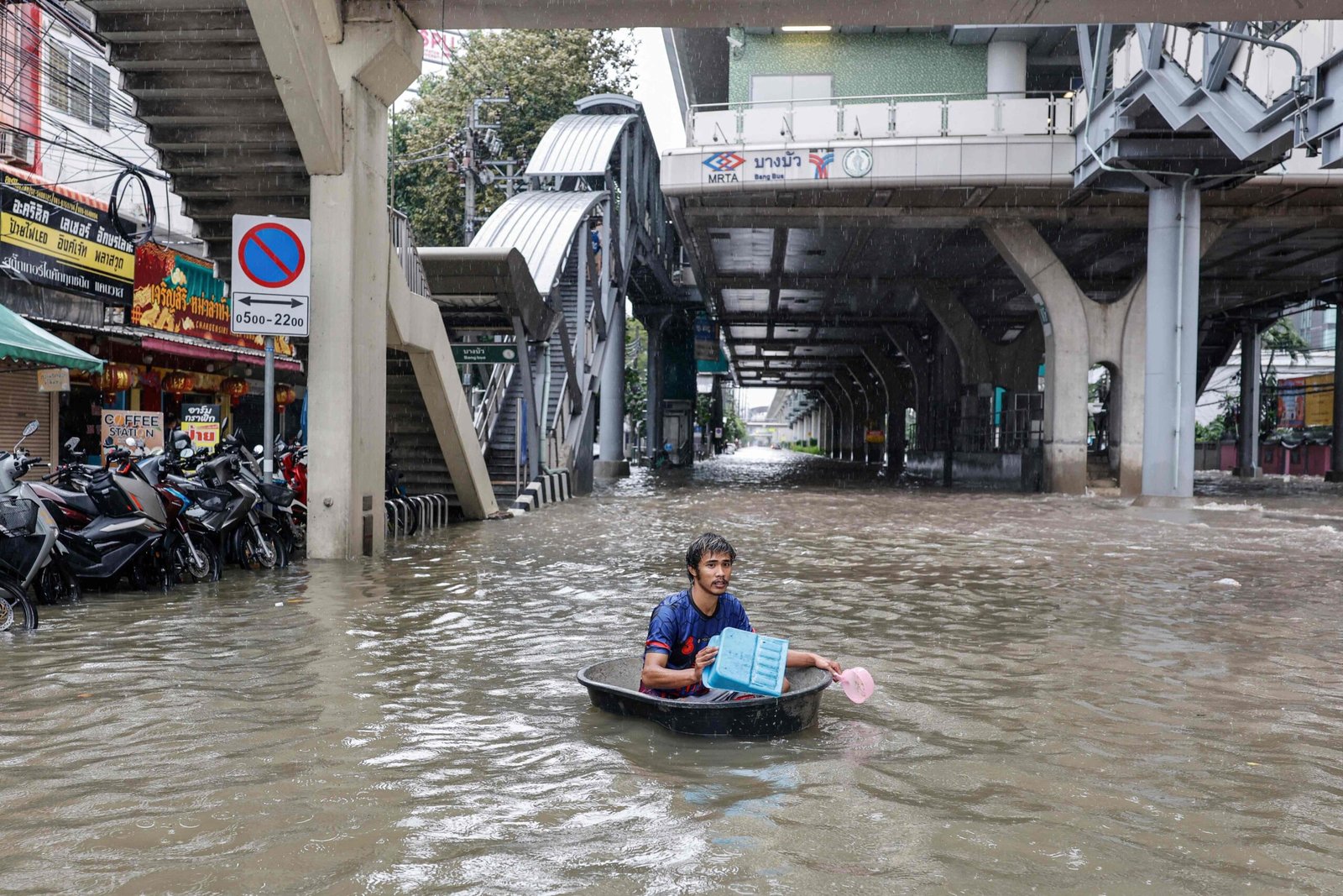A man uses a large plastic tube to wade through floodwaters in the Bang Bua district of Bangkok on Saturday. Photo: AFP